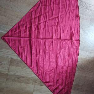 Ceris trekantig sidenscarf - Snygg trekantig scarf i starkt rosaröd färg, tillverkad i glansigt sidenliknande material. Perfekt att knyta runt halsen, väskan eller i håret för en cool och färgstark look. Enkel och stilren utan mönster.