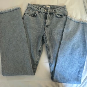 Ljusblå jeans med fransad kant - Ett par blå jeans med fransad kant. Jeansen har fyra fickor. Mycket gott skick, endast använd ett fåtal gånger. Passar perfekt till lite längre tjejer då benen är lite längre. (FRAKT INGÅR EJ)
