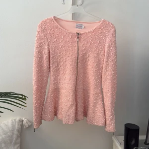 Aprikos cardigan jacka från Chloe London - Supersöt aprikos cardigan jacka från Chica London med strukturstickat tyg och glittriga detaljer. Jackan har rund halsringning, lång ärm och dragkedja framtill. Perfekt för dig som gillar en feminin och chic look. Otroligt vacker, svårt att fånga på bild.