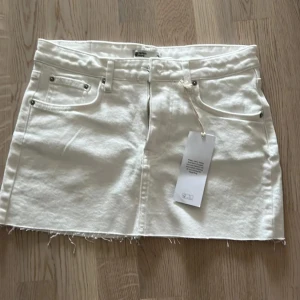 Vit jeanskjol från Perfect Jeans - Vit kort jeanskjol med rå kant och klassiska fem fickor. Prislappen är inte kvar och endast använd ett fåtal gånger. 
