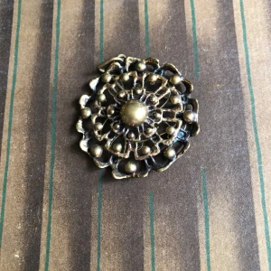 Vintage halsbandshänge i brons - Unikt runt halsbandshänge i brons med coolt, detaljerat filigranmönster och små kulor runt om. Perfekt för dig som gillar retro vibes och statement-smycken. Passar till en kedja för att skapa din egen look. Valo Koru Finland 70-tal. Hänget är 5cm i diameter 