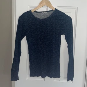 Mörkblå leopardmönstrad tajt långärmad tröja - Snygg långärmad tröja i mörkblått med svart leopardmönster. Tröjan är ribbad och har en tight passform med vågiga kanter vid ärmslut och nederkant. Köpt för några år sedan för 149 kr knappt använd.
