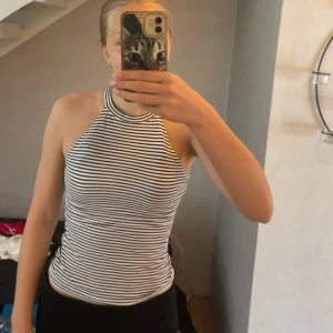 Randig halterneck linnetopp Gina Tricot - Säljer en svartvit randig halterneck linnetopp från Gina Tricot. Toppen är ärmlös med hög hals och smickrande passform. Perfekt till jeans eller kjol för en fräsch och trendig look.💗