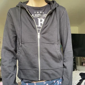 Svart zip hoodie - Svart hoodie från H&M Divided med dragkedja framtill, huva med snörning och två stora fickor. Perfekt för chill dagar eller när du vill ha en enkel och stilren look😻Bra att bara slänga på sig!! Aldrig använd, prislappar kvar!! Strl. M, men kan nog passa mindre också💋
