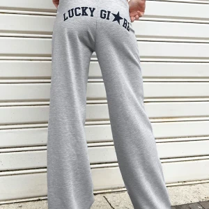 Grå mjukisbyxor med tryck - Snygga ljusgrå mjukisbyxor med marinblåa texten 'LUCKY GIRL' och stjärna baktill. Vida ben och lågmidjade
