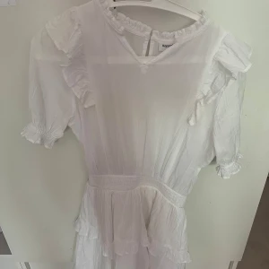 Vit volangklänning från Kappahl - ⚠️Använt en gång(ni ser hur de ser ut på sista bilden och jag är 158) och pris kan diskuteras vid snabbt köp⚠️Superfin vit klänning från Kappahl med volangdetaljer på axlar och kjol. Klänningen har v-ringning, korta ärmar med resår och en lätt, luftig känsla. Perfekt för sommarens alla tillfällen och ger en fin sommar vibe.