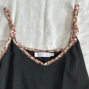 Svart linnetopp från Coster Copenhagen - Svart linnetopp från Coster Copenhagen med tunna axelband och kant  med leopardmönster. Snyggt kontrasterande detaljer. Perfekt att styla för vardag, fest eller sova i!