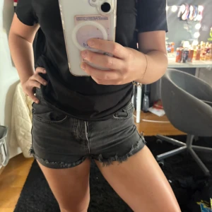 Svarta jeansshorts med fransig kant - Snygga svarta jeansshorts med rå, fransig kant och klassisk femficksdesign. Shortsen har låg/mellan midja och är perfekta för varma dagar. De är gjorda i mjukt denimtyg och har en mörk tvätt som ger en cool vibe. Från zara!! Skriv om du har frågor🩷🫶