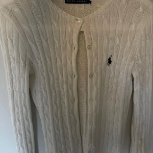 Vit kabelstickad kofta Ralph Lauren - Kabelstickad vit kofta från Ralph Lauren. Koftan har rund halsringning, knappar framtill och är långärmad. Stilren och snygg till jeans eller kjol.💗💗💗