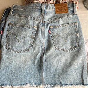 Levi's jeanskjol med slitna detaljer - ljusblå jeanskjol från Levis. (Liten i midjan) 