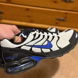 Nike Air sneakers  - Aldrig använda. Nike Air sneakers med vit mesh, svarta detaljer och blå swoosh. Skorna har synlig Air-sula, svarta snören och coola kontraster. Perfekta för dig som gillar sportig och modern stil. Bekväma och lätta med snygg design.