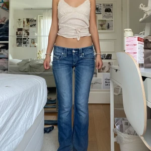 Blå bootcut jeans med detaljer - Snygga blå jeans från Maurices med bootcut-stil. De har dekorativa sömmar och knappar på bakfickorna. Perfekta för en avslappnad look.   Innerbenslängden:76cm och midjemått:39cm