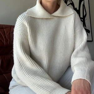 Vit ribbstickad tröja med krage - Superfin vit ribbstickad sweatshirt med bred krage. Tröjan har en relaxed passform och är tillverkad i ett mjukt, stickat material som känns både stilrent och skönt. Perfekt för lager-på-lager!
