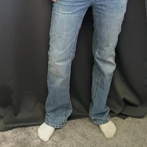 Blå jeans från Stradivarius, storlek 38 - Snygga blå jeans från Stradivarius i storlek 38. Jeansen har klassisk femficksdesign, raka ben och normal passform. Tillverkade i bomull med en lätt tvättad look och subtila slitningar.