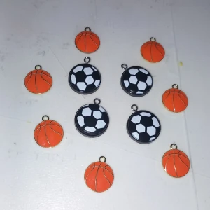 Hängsmycken basket & fotboll - Coola små hängsmycken i form av basketbollar och fotbollar. Perfekta att använda till armband, halsband eller örhängen. Basketbollarna är orange med svarta linjer och fotbollarna är svartvita. Passar dig som älskar sport och vill ha något unikt.