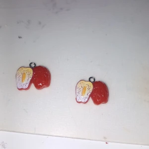 Söta örhängen med fruktmotiv - Unika örhängen formade som röda frukter, ena halvan är hel och andra halvan är delad med gul och vit insida. Perfekt accessoar för dig som gillar färgglada och lekfulla smycken.