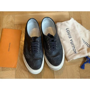Louis Vuitton Trocadero sneakers - Louis Vuitton Trocadero sneakers – strl 43 (EU) Snygga sneakers i Monogram Eclipse canvas från Louis Vuitton. Svart läderdetalj vid hälen och vit sula.   Skick: Använda, men i helt okej skick (se bilder)  Ingår: – Original dustbag – Kvitto – Kuvert för kvitto från LV