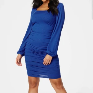 Blå ribbad kortklänning med långa ärmar - Snygg blå kortklänning med ribbad struktur och långa puffärmar. Klänningen har en fyrkantig ringning och smickrande rynkade detaljer längs sidorna. Perfekt för dig som vill sticka ut med en färgstark look. Aldrig använd, prislapp sitter kvar.