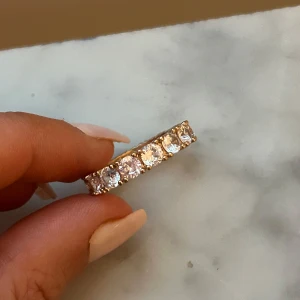 Guldfärgad ring med stora stenar - Snygg guldfärgad ring med stora, gnistrande klara stenar runt hela bandet. 