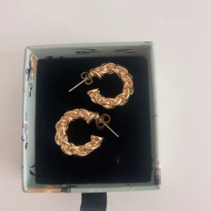 Flätade guldiga örhängen  - Snygga örhängen i form av flätad design i guld. Knappt använt, köpt från glitter!