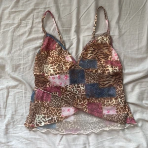 Leopardmönstrad linnetopp - Säljer en tunn och luftig linnetopp i mesh med leopard- och tigrar-mönster i brunt, beige, blått och rosa. Toppen har smala axelband, omlott-detalj framtill och vågig kant nertill. Tyget är inte genomskinligt men är lite see-through. Jättegullig och perfekt för sommaren. Jag säljer den då den inte passade mig.