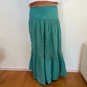 Turkos långkjol med grafiskt mönster - Superskön turkos långkjol med coolt mönster. Modellen på bild är 171 cm lång. 