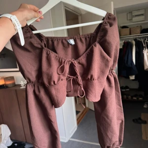 Brun croppad blus med snörning - Superfin brun croppad blus från med långa puffärmar och snygg snörning framtill.