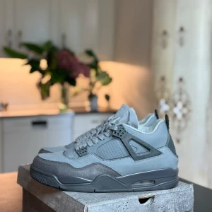 Nike Air Jordan 4 Cool Grey sneakers - Snygga Nike Air Jordan 4 i helgrått med coola detaljer och signatur Jumpman-logga. Skorna har en mix av mocka och syntet, meshpaneler och klassisk snörning. Perfekta för dig som gillar streetstyle och vill sticka ut med en ikonisk siluett.