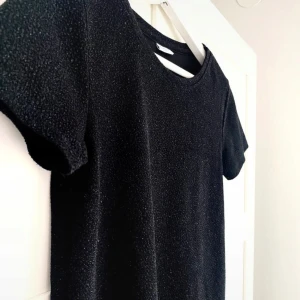 Glittrig t-Shirt  - Svart glittrig topp från Jacqueline de Yong i storlek XS.