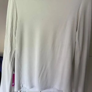 Vit långärmad tröja från 157 - En basic vit långärmad tröja från 157 i storlek S. Tröjan har en enkel och clean design med rund halsringning och är tillverkad i mjuk bomull. Perfekt att styla med jeans eller under en skjorta för en avslappnad look. Fläckar syns på bild 2 och 3