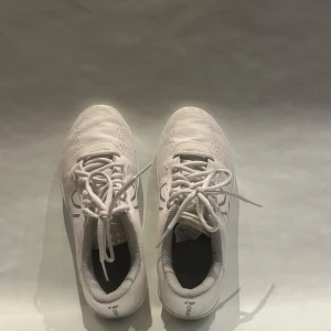 Vita sneakers från Domyos - Fräscha vita sneakers från Domyos med snygga grå detaljer på sidorna. Skorna har snörning, perforerade partier för extra ventilation och en platt sula med vågmönster undertill. Perfekta för dig som gillar en clean och sportig look.