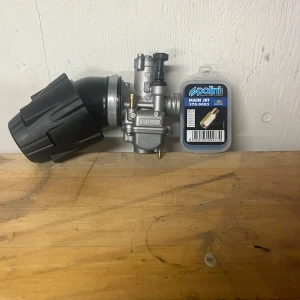 Polini CP 19 - Polini CP 21 är en förgasare perfekt för dig som vill trimma din moped eller scooter. Med robust design och tillhörande main jet får du bättre prestanda och acceleration. Passar dig som gillar att meka och optimera din motor för en roligare körupplevelse.