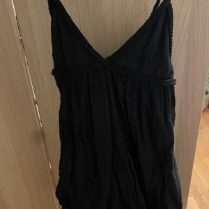 Svart klänning zara  - Snygg svart mini  klänning med flätade axelband och detaljer under bysten. Perfekt för en stilren look. Klänningen är i linne och köpt från zara för ca 3 år sedan, har inbyggda shorts ocskå! Köpt för 500kr 