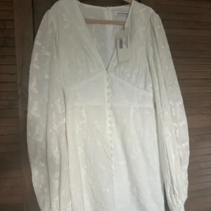Vit klänning från Adoore - Superfin vit långklänning från Adoore med broderade små blommor, v-ringning och knappar framtill. Använd endast en gång, lapp står kvar. Nypris, 1495kr. 