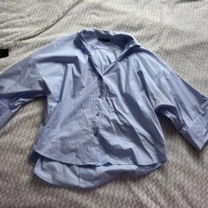 Ljusblå skjorta från Zara, S - Säljer en ljusblå skjorta från Zara i storlek S. Skjortan har klassisk krage, knappar framtill och breda manschetter med tre knappar på varje ärm. Tillverkad i bomull och har en loose passform med lite längre bakstycke.