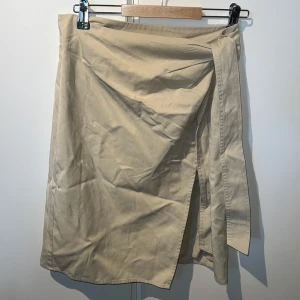 Beige omlottkjol från Samsøe Samsøe - Stilren beige omlottkjol från Samsøe Samsøe i bomull. Kjolen har en enkel design med knyt i sidan och rak passform som ger en clean och avslappnad look. Perfekt att matcha med sneakers eller boots för en cool vibe. Så jäkla snygg men tyvärr aldrig använd. Passar mellan S-L. Nypris 1199kr❤️