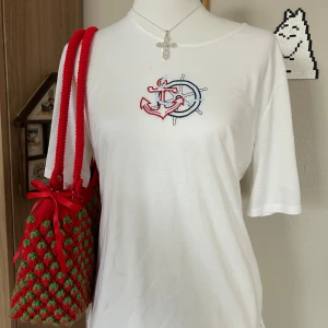 Broderad t-shirt - Vit t-shirt med kort ärm och broderat motiv av en röd  ankare och ett blått skeppsratt på bröstet. T-shirten har en klassisk passform och är gjord i mjukt bomullstyg. Perfekt för en chill och stilren look.