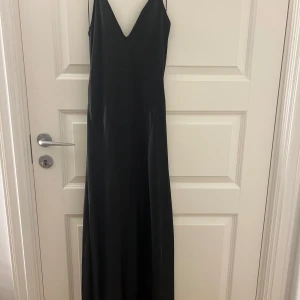Klänning ifrån Zara med öppen rygg - Elegant svart långklänning med öppen rygg ifrån Zara. Banden är uppsydda något annars är den som ny.
