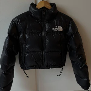 Svart pufferjacka från The North Face - Säljer en svart pufferjacka från The North Face. Jackan är croppad med dragkedja och har långa ärmar. Jackan är i fint skick, säljer då jag ej får användning av den. Pris kan diskuteras vid snabb affär. 