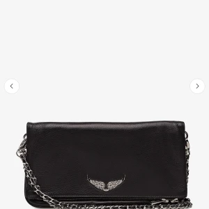Zadig väska  - Snygg svart Zadig väska i skinn med en kedja och ett dekorativt Zadig emblem framtill. Väskan har en praktisk dragkedja på baksidan för extra förvaring. Perfekt för att ge din outfit en edgy touch. Bilder från Boozt, bilder på väskan går att få privat. Pris går att diskuteras vid snabb affär. Nypris - 3600kr