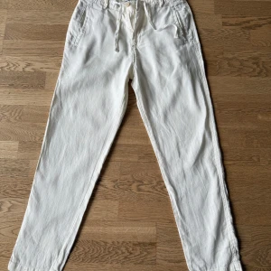 Vita linnebyxor från Zara - Snygga vita linnebyxor med avslappnad passform och snörning i midjan. Perfekta för varma dagar med sin lätta och luftiga känsla. Byxorna har både fram- och bakfickor för extra funktionalitet. Knappt använda. Priset är inte fast och går och diskutera.  