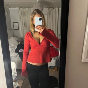 Röd omlottopp med knyt - Snygg röd omlottopp med knyt i midjan och v-ringad design. Knappt använd och säljer då jag inte använder den 💕