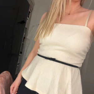 Vit pemplum topp med rosett i midjan - Jättefin vit topp i storlek S med svart detalj i midjan köp på arkivet men från Holly & White (Lindex) 