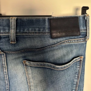 Jeans från J.Lindberg - Blåa jeans från J Lindberg med slitningar. Riktigt snygga och sköna byxor som är perfekt till våren. I storlek 32/32. Skriv gärna vid frågor!