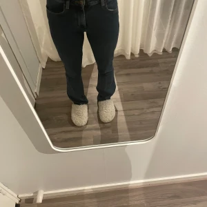 Blå jeans från Wrangler - Säljer ett par klassiska blå jeans från Wrangler. De har en bootcut passform och är mid midjade. Jeansen har används och har hål i ena fickan och är lite slitna vid bena 