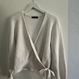 Vit ribbad omlottkofta  - Säljer en stilren vit ribbad omlottkofta från M&S collection. Koftan har långa ärmar och knytband i midjan för en justerbar passform. Perfekt för lager-på-lager under kyligare dagar.