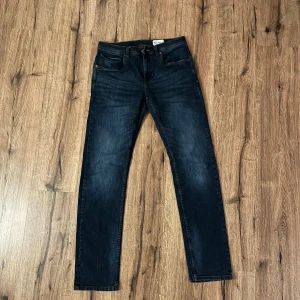 Mörkblå jeansbyxor - Snygga mörkblå jeansbyxor med en klassisk design. De har en normal passform och är perfekta för en avslappnad stil. Byxorna har fem fickor och en dragkedja med knappstängning.