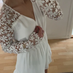 Vit klänning med spetsärmar -  vit klänning med v-ringad design,  spetsärmar och en omlott-look med en lätt volangdetalj vid fållen, säljer eftersom den är för stor på mig. Stl 36 (S) aldrig använd