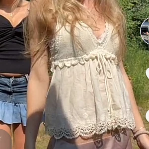 Vit spetsprydd topp från Zara - Säljer en söt vit topp från Zara med spetsdetaljer och knytband framtill. Toppen har en vacker virkad överdel och ärmlös design, perfekt för sommardagar. Den har en luftig passform och fina broderade kanter. Trådet har gått upp lite på snöret men inget som syns när den är på (sista bilden).