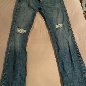 Blå jeans från Lee - Snygga blå jeans från Lee med slitna detaljer på knäna. De har en klassisk femficksdesign och en bekväm passform. Perfekta för en avslappnad stil.